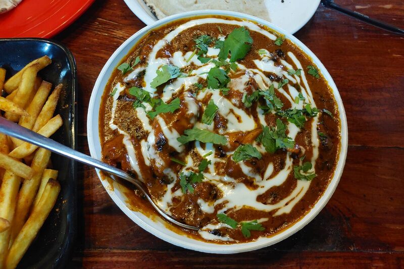 Bowl of butter chicken with a swirl of cream and rice
