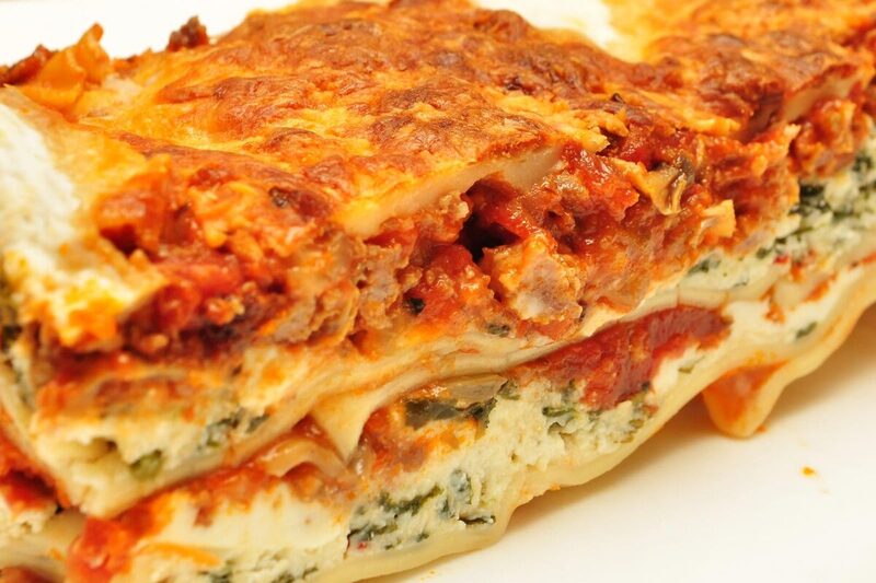 Slice of baked lasagne alla bolognese showing layers of pasta, ragu, and besciamella