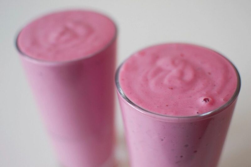 Glass of mixed berry smoothie topped with fresh berries
