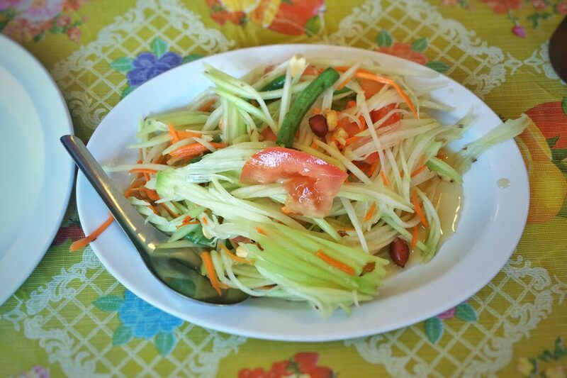 Plate of Thai som tam, shredded green papaya with peanuts, chili, and tomato