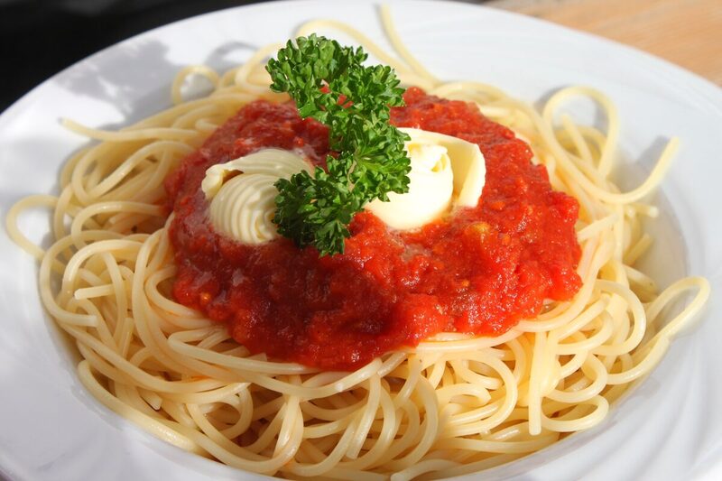 Bowl of spaghetti in tomato sauce topped with torn basil leaves